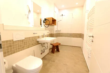 innenliegendes Badezimmer mit bodentiefer Echtglas-Dusche, WC, Kosmetikspiegel, Fön, Ablageflächen und elektrischem Handtuchtrockner