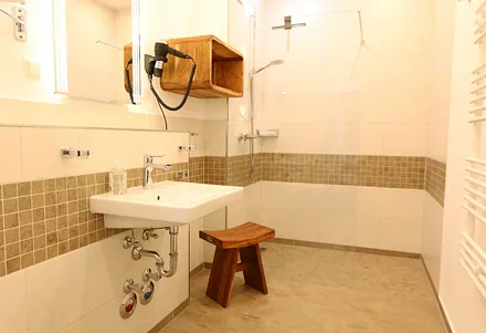 innenliegendes Badezimmer mit bodentiefer Echtglas-Dusche, WC, Kosmetikspiegel, Fön, Ablageflächen und elektrischem Handtuchtrockner