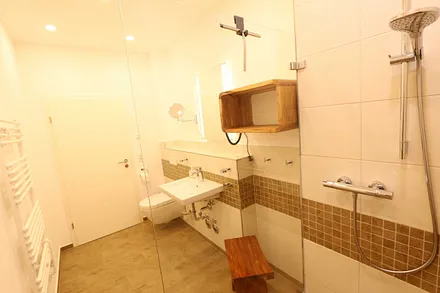 innenliegendes Badezimmer mit bodentiefer Echtglas-Dusche, WC, Kosmetikspiegel, Fön, Ablageflächen und elektrischem Handtuchtrockner