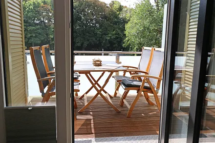 Bangkirai belegter, windgeschützer Südbalkon mit Teakholz-Sitzgruppe, Insektenschutzgitter und Sonnenschirm