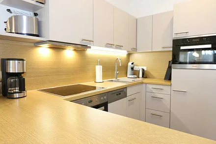 Küchenzeile mit Mikrowelle, Backofen, Induktionskochfeld, Geschirrspüler, Kaffeemaschine, Pad-Maschine (Senseo), Wasserkocher, Eierkocher, Toaster, Handmixer und Kühlschrank mit Gefrierfach 