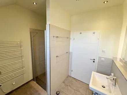 Tageslichtbadezimmer mit ebenerdiger Glasdusche, Waschtisch, WC, Waschmaschine, Kosmetikspiegel, Fön und beheizbarem Handtuchtrockner