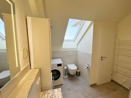 Tageslichtbadezimmer mit ebenerdiger Glasdusche, Waschtisch, WC, Waschmaschine, Kosmetikspiegel, Fön und beheizbarem Handtuchtrockner