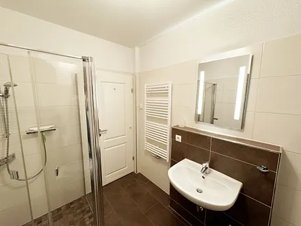 Badezimmer mit Dusche, WC, Kosmetikspiegel, Fön, Waschbecken und Handtuchwärmeheizkörper