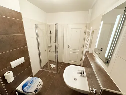 Badezimmer mit Dusche, WC, Kosmetikspiegel, Fön, Waschbecken und Handtuchwärmeheizkörper