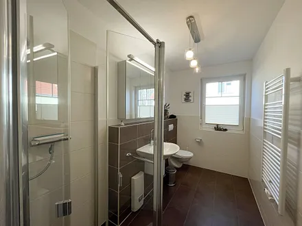 komfortables Badezimmer mit WC, Waschbecken, Fön, Dusche und Handtuchwärmeheizkörper