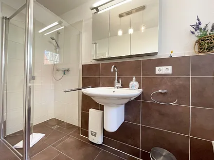 komfortables Badezimmer mit WC, Waschbecken, Fön, Dusche und Handtuchwärmeheizkörper