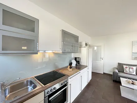 Küchenzeile mit Cerankochfeld, Backofen, Dunstabzugshaube, Kühlschrank mit Gefrierfach, Spülmaschine, Kaffeemaschine, Mikrowelle, Wasserkocher, Toaster und diverse Küchenutensilien