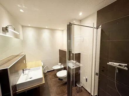 Badezimmer mit bodengleicher Dusche, Waschtisch, WC, Bidet, Handtuchheizung, Waschmaschine (AEG Lavamat), Spiegelleuchte und Fön