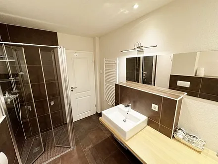 Badezimmer mit bodengleicher Dusche, Waschtisch, WC, Bidet, Handtuchheizung, Waschmaschine (AEG Lavamat), Spiegelleuchte und Fön