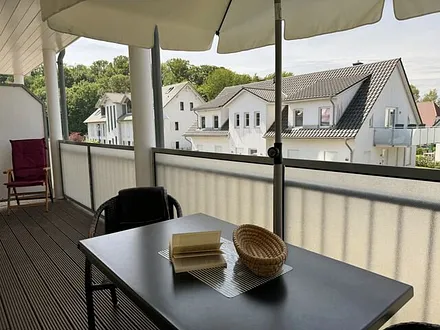 12 m² großer überdachter, bestuhlter Balkon (Süd/West) mit Sonnenschirm (transparente Balkonverkleidung)