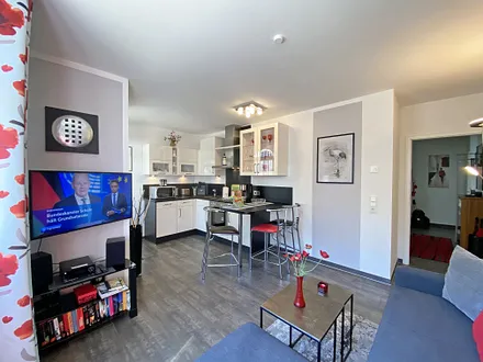 Wohnzimmer mit TV und Blick zur Küchenzeile