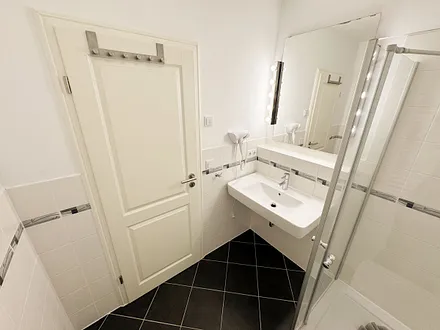 Badezimmer mit ebenerdiger Glasdusche, WC, Fön und Handtuchheizkörper