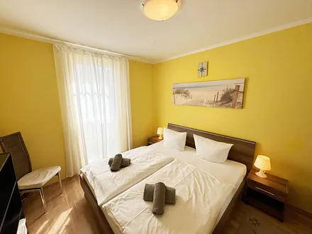 komfortables Schlafzimmer mit Doppelbett (1,80 m x 2,00 m), hochwertigen Matratzen, verstellbaren Lattenrosten, 2 Nachttischlampen, Flachbild-TV und Kleiderschrank