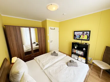 komfortables Schlafzimmer mit Doppelbett (1,80 m x 2,00 m), hochwertigen Matratzen, verstellbaren Lattenrosten, 2 Nachttischlampen, Flachbild-TV und Kleiderschrank