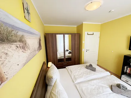 komfortables Schlafzimmer mit Doppelbett (1,80 m x 2,00 m), hochwertigen Matratzen, verstellbaren Lattenrosten, 2 Nachttischlampen, Flachbild-TV und Kleiderschrank