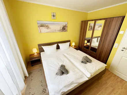 komfortables Schlafzimmer mit Doppelbett (1,80 m x 2,00 m), hochwertigen Matratzen, verstellbaren Lattenrosten, 2 Nachttischlampen, Flachbild-TV und Kleiderschrank