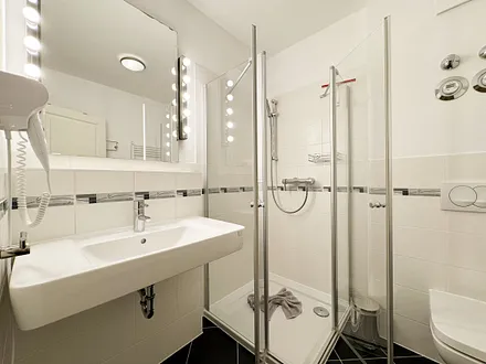 Badezimmer mit ebenerdiger Glasdusche, WC, Fön und Handtuchheizkörper