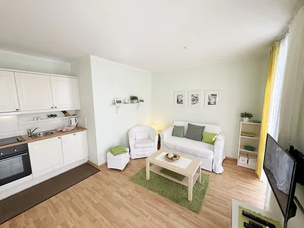  Wohnbereich mit einer Couch (Aufbettungsmöglichkeit für 3. Person – 1,20 m x 1,96 m), einen Sessel, Couchtisch, Leselampe, LED-TV und eine Mini-Stereoanlage mit CD und DVD-Player 