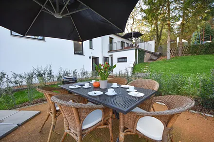 Terrasse mit Sonnenschirm und Kohlegrill von Weber