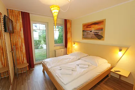 Schlafzimmer mit Doppelbett (1,80 m x 1,90 m), Nachttischkonsolen, Smart-TV, geräumiger Kleiderschrank, großer Wandspiegel und einem Herrendiener mit Sitzmöglichkeit