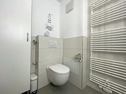 Badezimmer mit Dusche, WC, Kosmetikspiegel, Waschtisch und einem mobilen Wäscheständer