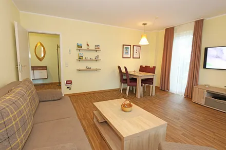 Wohnzimmer mit Couch (Aufbettung für 3./4. Person, 1,50 m  x 2,00 m), Couchtisch, Leselampe, Smart-TV, Radio mit CD-Player