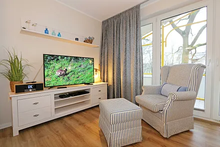 Wohnbereich mit einer gemütlichen Couch (Aufbettung für 3. und 4. Person, Liegefläche 1,60 m x 2,00 m), Couchtisch, gemütlichen Ohrensessel, Leselampe, Lowboard mit Smart-TV und Blu Ray-Player