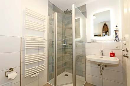 Badezimmer mit Glasdusche (niedriger Einstieg), Waschplatz, WC, Kosmetikspiegel, Fön und Handtuchtrockner