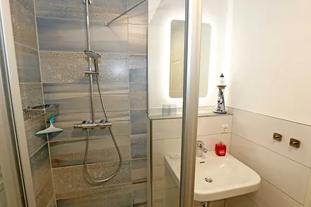 Badezimmer mit Glasdusche (niedriger Einstieg), Waschplatz, WC, Kosmetikspiegel, Fön und Handtuchtrockner