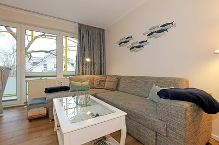 Wohnbereich mit einer gemütlichen Couch (Aufbettung für 3. und 4. Person, Liegefläche 1,60 m x 2,00 m), Couchtisch, gemütlichen Ohrensessel, Leselampe, Lowboard mit Smart-TV und Blu Ray-Player