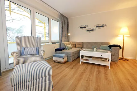 Wohnbereich mit einer gemütlichen Couch (Aufbettung für 3. und 4. Person, Liegefläche 1,60 m x 2,00 m), Couchtisch, gemütlichen Ohrensessel, Leselampe, Lowboard mit Smart-TV und Blu Ray-Player