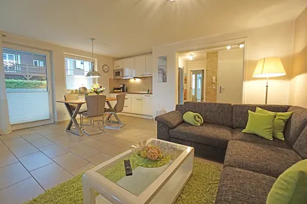 Wohnzimmer mit Esstisch und vollausgestatteter Küchenzeile