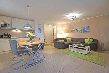 Wohnzimmer mit Esstisch und vollausgestatteter Küchenzeile