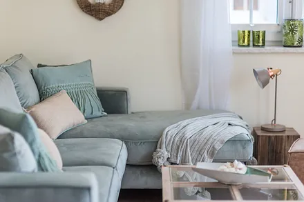 Wohnbereich mit Couch, Couchtisch, Sessel, Leselampe, Sideboard, Smart-TV, DAB Radio, Blu Ray Player sowie durchgängige Fensterfront mit fantastischem Panorama- und Meerblick