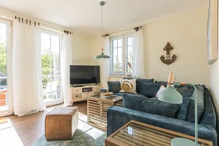 Wohnbereich mit Couch, Couchtisch, Leselampe, Sideboard, Smart-TV, DAB Radio, Blu Ray Player sowie durchgängige Fensterfront mit fantastischen Panorama- und Meerblick