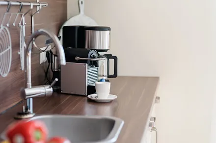 Küchenzeile mit Cerankochfeld, Dunstabzugshaube, Backofen, Geschirrspüler, Kühlschrank mit Eisfach, Kaffeemaschine, Wasserkocher, Toaster und diversen Küchenutensilien