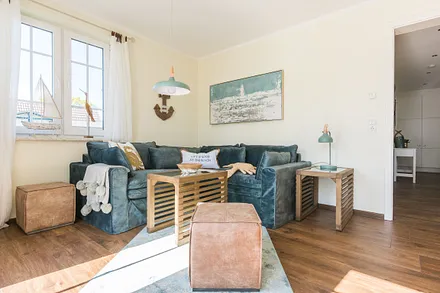 Wohnbereich mit Couch, Couchtisch, Leselampe, Sideboard, Smart-TV, DAB Radio, Blu Ray Player sowie durchgängige Fensterfront mit fantastischen Panorama- und Meerblick