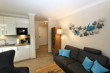 Wohnzimmer mit gemütlicher Couch, Couchtisch, Ohrensesel mit Hocker, Leselampe, Smart-TV, Radio mit CD-Player und Bluetooth/USB sowie eine Vitrine