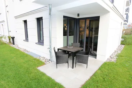 bestuhlte Terrasse (Süd) mit Sonnenschirm und kleinem Gartenanteil