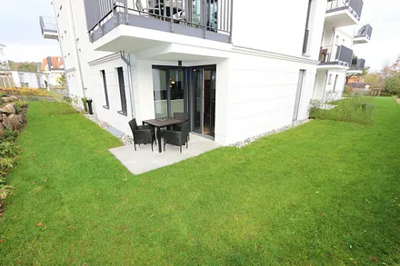 bestuhlte Terrasse (Süd) mit Sonnenschirm und kleinem Gartenanteil