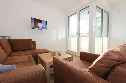 Wohnbereich mit Eckcouch, Couchtisch, Sessel, Vitrine, Smart-TV mit integriertem Radio, USB-Anschluss und Bluetooth