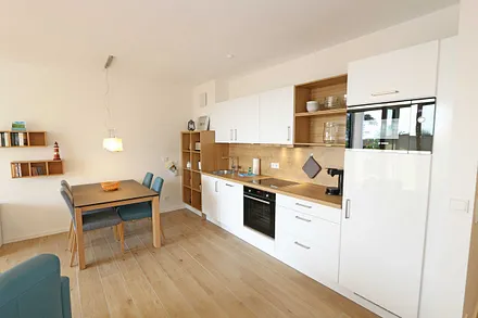 offener Wohn-/ Küchenbereich mit Couchtisch, Sessel, Stehlampe, Sideboard, bequemer Ledercouch, Smart-TV von Loewe mit Blu-Ray-Player und Musik-CD`s