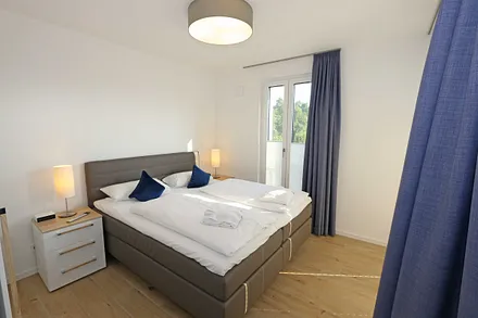 Schlafzimmer mit Boxspringbett (1,80 m x 2,00 m) in Komforthöhe, Nachttischablagen mit Wandleuchten, großzügiger Kleiderschrank und Smart-TV