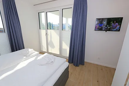 Schlafzimmer mit Boxspringbett (1,80 m x 2,00 m) in Komforthöhe, Nachttischablagen mit Wandleuchten, großzügiger Kleiderschrank und Smart-TV