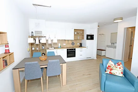 offener Wohn-/ Küchenbereich mit Couchtisch, Sessel, Stehlampe, Sideboard, bequemer Ledercouch, Smart-TV von Loewe mit Blu-Ray-Player und Musik-CD`s