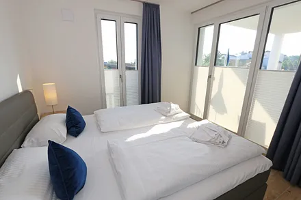 Schlafzimmer mit Boxspringbett (1,80 m x 2,00 m) in Komforthöhe, Nachttischablagen mit Wandleuchten, großzügiger Kleiderschrank und Smart-TV