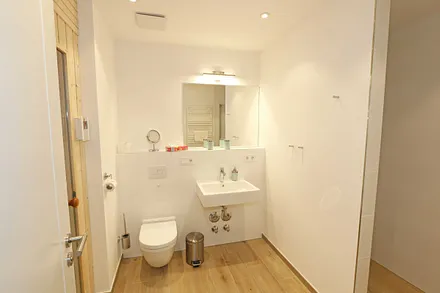 innenliegendes Badezimmer mit Waschtisch, Wandspiegel, ebenerdige Regendusche, WC, Fön, Handtuchtrockner, Kosmetikspiegel und Infrarotsauna