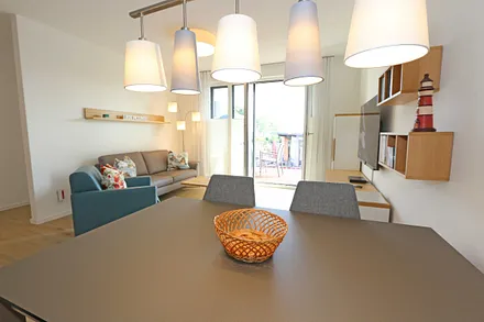 offener Wohn-/ Küchenbereich mit Couchtisch, Sessel, Stehlampe, Sideboard, bequemer Ledercouch, Smart-TV von Loewe mit Blu-Ray-Player und Musik-CD`s