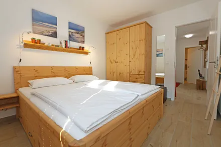 Schlafzimmer mit Doppelbett (1,80 m x 2.00 m), verstellbare Lattenroste, Nachttischablagen, Ganzkörperspiegel, Kleiderablage, geräumiger Kleiderschrank, Smart-TV sowie Verdunklungs-Vorhängen